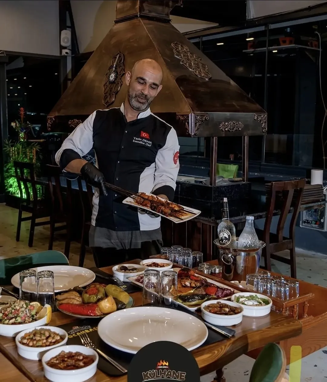 Usta ocağın başında, şişi ateşe yakın tutarak çeviriyor